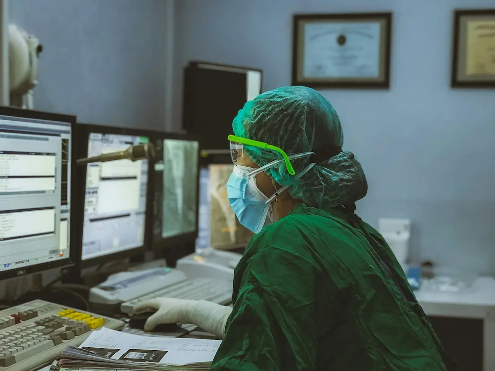 Professionnel de santé en tenue chirurgicale travaillant sur système informatique médical