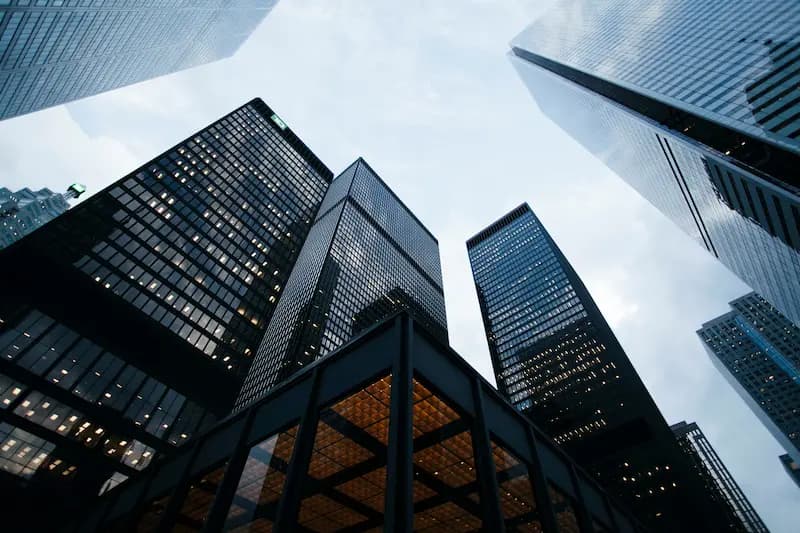 Vue en contre-plongée d'immeubles de bureaux modernes illustrant l'approche hybride multi-sites